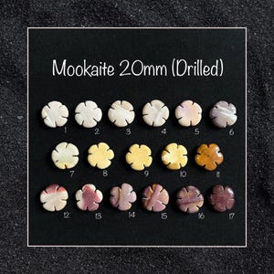 May include: A selection of 17 drilled Mookaite gemstone beads, each measuring 20mm in diameter. The beads are arranged in three rows, with each row featuring a different colour variation of the stone. The colours range from white and cream to brown and purple.