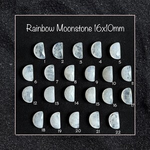 Könnte beinhalten: Eine Sammlung von zweiundzwanzig Regenbogen-Mondstein-Cabochons, jeweils etwa 1,6 cm x 1 cm, in Reihen angeordnet. Die Edelsteine sind ein durchscheinendes Weiß mit einem subtilen irisierenden Schimmer. Der Text "Rainbow Moonstone 16x10mm" ist oben angezeigt.