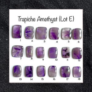 May include: Eighteen Trapiche Amethyst gemstones are displayed, each showcasing a distinctive pattern of purple and white inclusions. The rectangular gemstones have rounded corners and are numbered from 1 to 18.