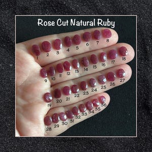 Puede incluir: Una colección de 36 rubíes naturales de talla rosa, que van desde pequeños hasta grandes. Los rubíes se muestran en una mano, con cada piedra numerada.