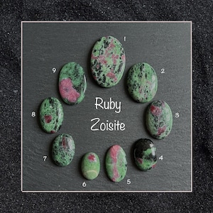 May include: Nine oval-shaped ruby zoisite gemstones in various shades of green and pink with black flecks. The gemstones are numbered 1 through 9.