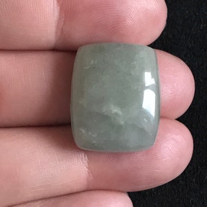 Pode incluir: Uma gema cabochão retangular de cor verde claro, com uma superfície lisa e polida.