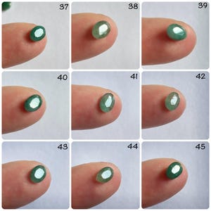Pu&ograve; includere: Una collezione di 9 pietre preziose verdi di forma ovale, ciascuna esposta su un dito, con i numeri da 37 a 45 etichettati sopra.