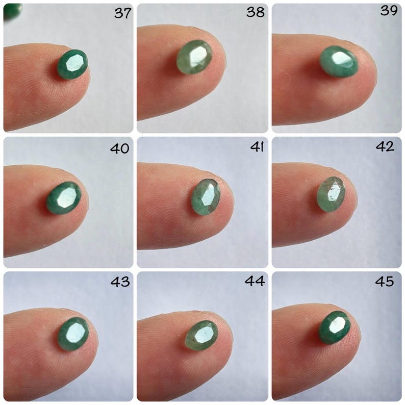 Pu&ograve; includere: Una collezione di 9 pietre preziose verdi di forma ovale, ciascuna esposta su un dito, con i numeri da 37 a 45 etichettati sopra.