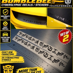 May include: A set of two black vinyl decals featuring 24 cyberglyphic symbols for a 2012 Camaro Bumblebee. The decals are displayed next to a metal ruler showing a length of approximately 30 cm, with text reading 2012 CAMARO BUMBLEBEE.