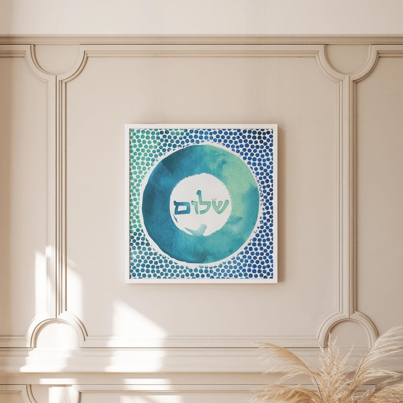 May include: A framed watercolour painting with a blue and green circle design. The circle has a white centre with the Hebrew word "Shalom" written in it. The background is a white wall with decorative moulding.