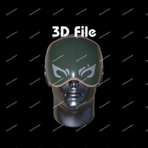 Może przedstawiać: Plik 3D zielonej maski do spania z białymi wzorami w kształcie skrzydeł i beżowym wykończeniem, spoczywającej na metalowej głowie manekina. Biały tekst "3D File" jest wyświetlany nad maską na czarnym tle.