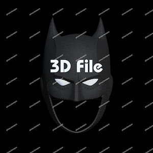 May include: A black Batman mask with pointed ears and white eye openings. The mask has a textured surface and the text "3D File" is displayed in white across the front. The mask is set against a black background.