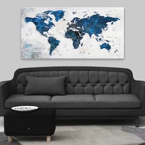 May include: A dark gray sofa with a tufted back and a black ottoman in front of it. A world map with blue and white watercolor accents hangs on the wall behind the sofa.
