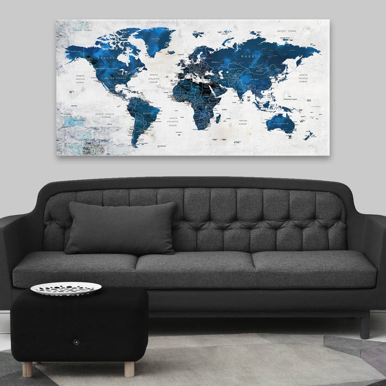May include: A dark gray sofa with a tufted back and a black ottoman in front of it. A world map with blue and white watercolor accents hangs on the wall behind the sofa.