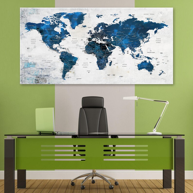 May include: A blue and white world map print hanging on a wall above a green desk with a black office chair. The map is a watercolor style with a white background and blue continents.