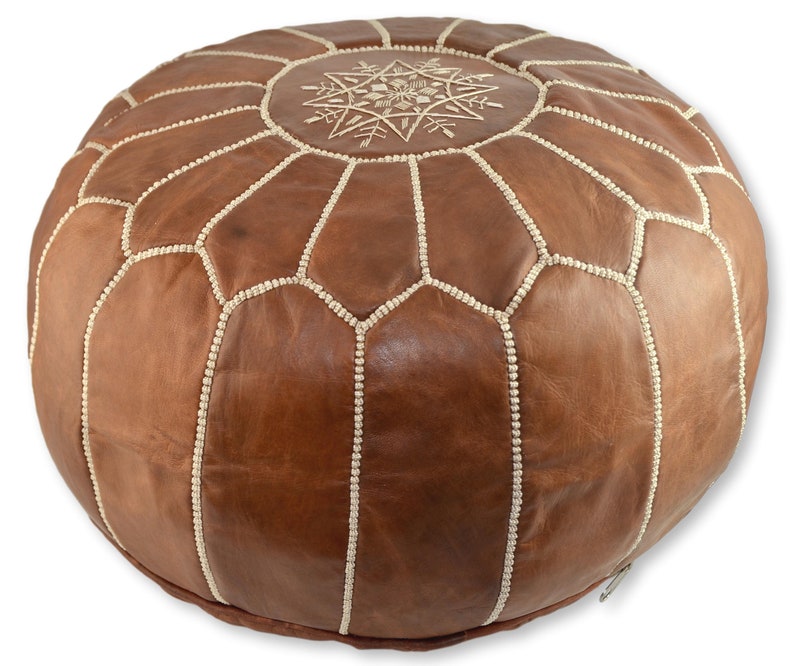 May include: A brown leather pouf with white stitching and a white embroidered star design on the top.