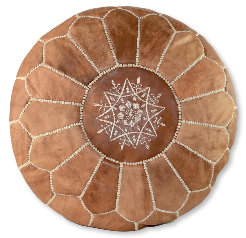 May include: A brown leather pouf with white stitching and a white embroidered star design in the center.