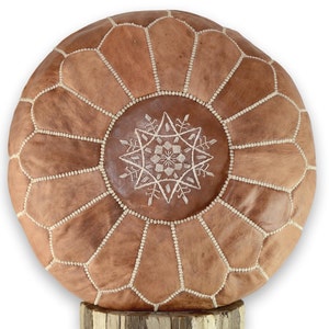 May include: A round brown leather pouf with white stitching and a white embroidered star design.