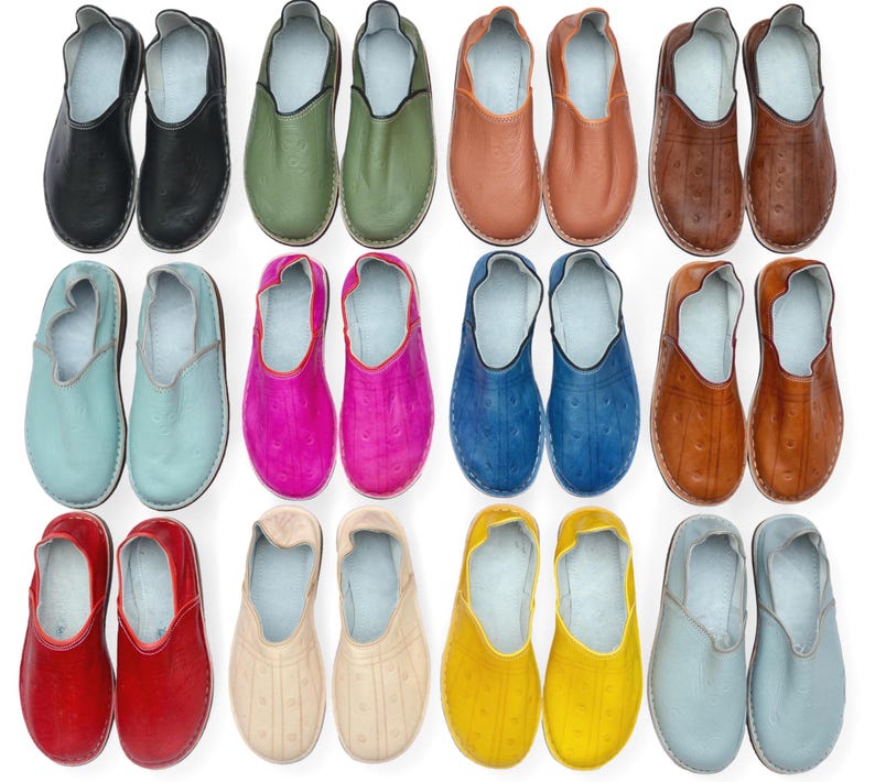 May include: A collection of twelve pairs of slip-on shoes arranged in a grid, featuring various solid colors including black, olive green, tan, brown, light blue, magenta, royal blue, red, beige, yellow, and grey, all with a smooth finish.