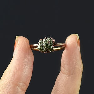 Op de afbeelding: Een ring met een groene edelsteen gezet in een roségouden band.