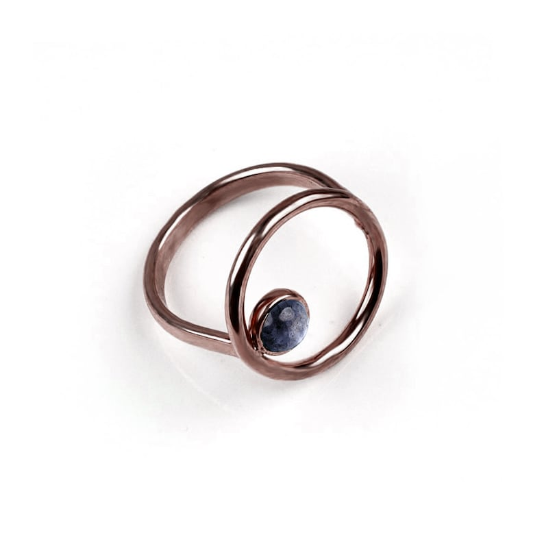 Puede incluir: Un anillo de oro rosa con una sola piedra preciosa azul engastada en un dise&ntilde;o circular.