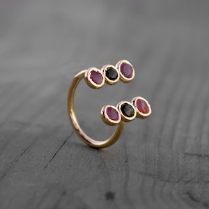 Peut inclure: Une bague en or avec une double rangée de cinq pierres précieuses. Les pierres précieuses sont rouges et noires.