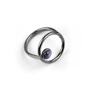 Puede incluir: Un anillo de plata con una piedra preciosa azul engastada en un dise&ntilde;o circular.