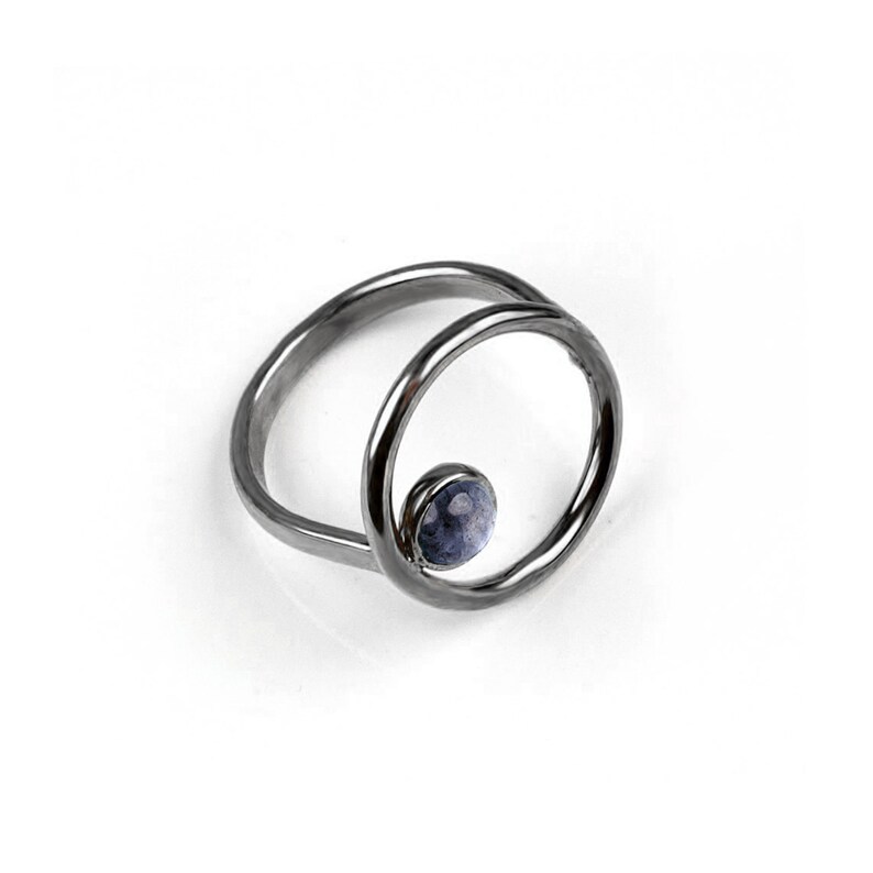 Puede incluir: Un anillo de plata con una piedra preciosa azul engastada en un dise&ntilde;o circular.