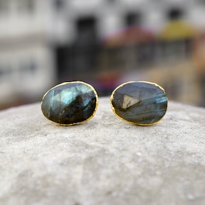 Peut inclure: Une paire de boucles d'oreilles ovales avec une pierre précieuse de labradorite bleu foncé sertie d'or.