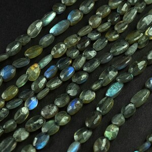 Puede incluir: Una hebra de cuentas ovaladas de piedra preciosa labradorita. Las cuentas son una mezcla de colores verde oscuro, azul y dorado con un brillo iridiscente.