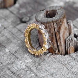 Puede incluir: Un anillo de oro con una banda de peque&ntilde;as piedras facetadas transparentes. El anillo est&aacute; sobre un trozo de madera desgastada.