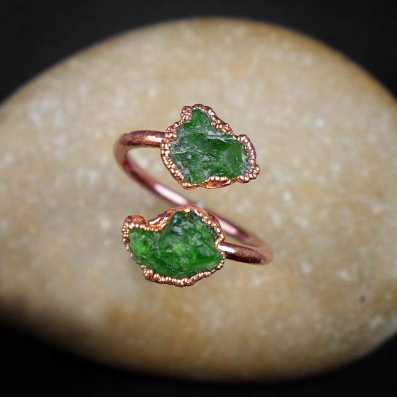 May include: A copper wire ring with two green peridot stones wrapped around the band.