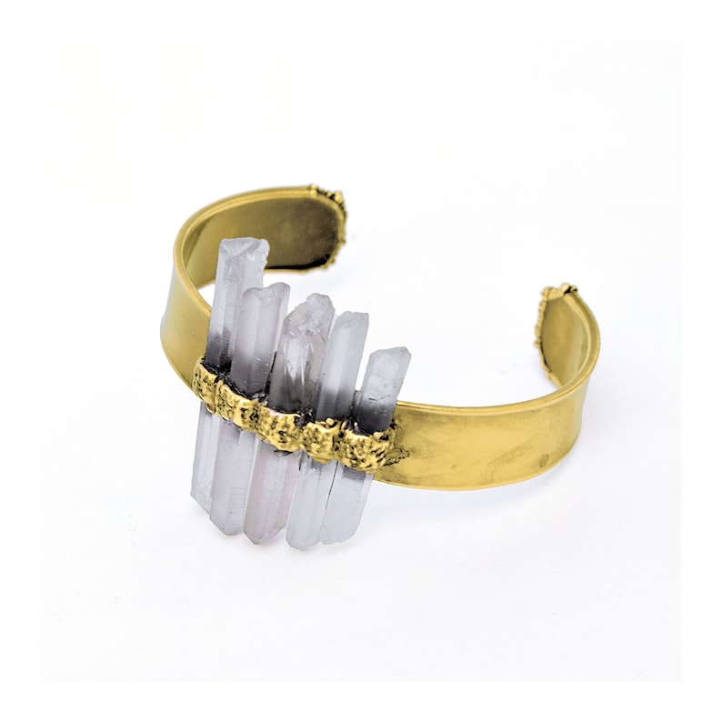 May include: A gold metal cuff bracelet with a cluster of clear quartz crystals set in the centre.
