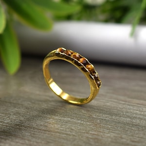 May include: A gold ring with a row of brown tiger's eye stones set in the band.