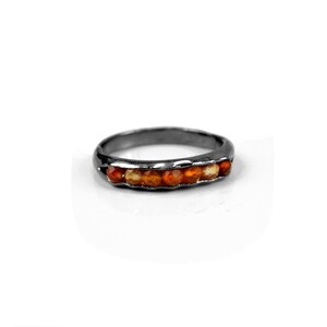 May include: A silver band ring with a row of orange carnelian gemstones.