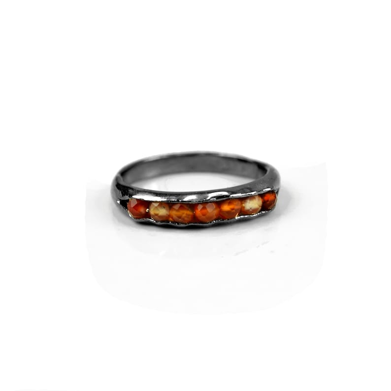 May include: A silver band ring with a row of orange carnelian gemstones.