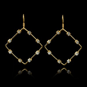 May include: A pair of gold hoop earrings with clear, faceted gemstones set in a square shape.
