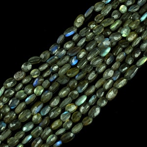Puede incluir: Una hebra de cuentas ovaladas de piedra preciosa de labradorita. Las cuentas son de color verde oscuro con destellos azules iridiscentes.