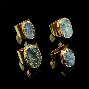 Puede incluir: Cuatro anillos de oro con engastes de piedras preciosas azules. Los anillos son de forma ovalada y tienen una banda de oro texturizada.