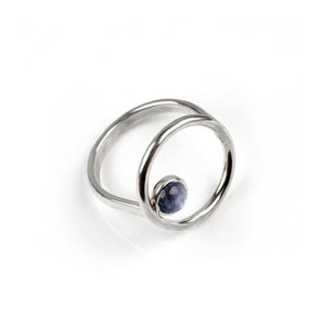 Puede incluir: Un anillo de plata con una piedra preciosa azul engastada en un dise&ntilde;o circular.