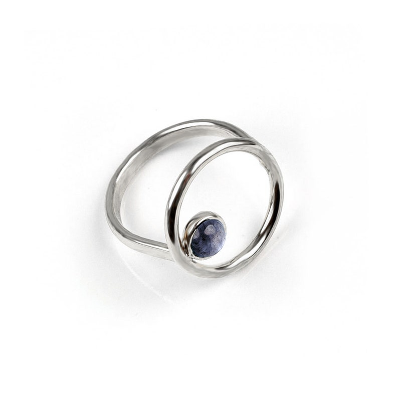 Puede incluir: Un anillo de plata con una piedra preciosa azul engastada en un dise&ntilde;o circular.