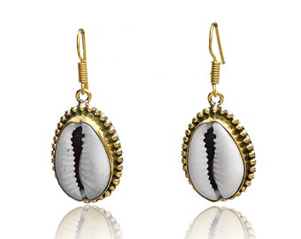 May include: A pair of gold-tone earrings with a white cowrie shell design. The earrings have a simple hook closure.