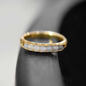 May include: A gold band ring with a row of white gemstones.