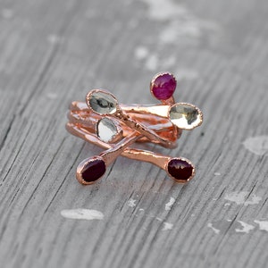 Könnte beinhalten: Ein Ring aus Roségold mit mehreren Bändern und fünf kleinen Steinen. Die Steine sind eine Mischung aus klar und rosa.