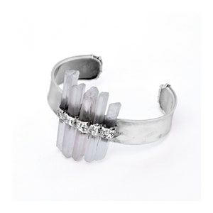 May include: A silver cuff bracelet featuring a cluster of light purple and white crystal points. The crystals are set in a row of small silver beads.