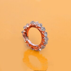 Puede incluir: Un anillo de oro rosa con una banda de cristales transparentes y facetados.