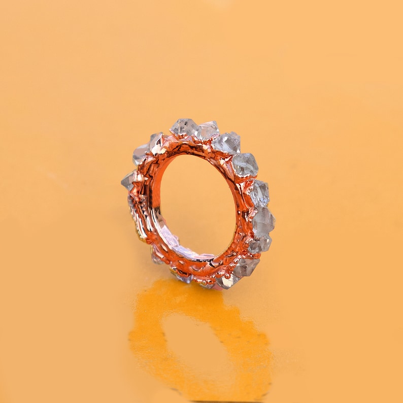 Puede incluir: Un anillo de oro rosa con una banda de cristales transparentes y facetados.