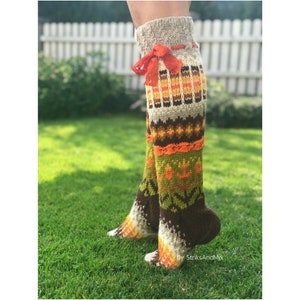 May include: A pair of long, knitted socks with a colourful geometric pattern in shades of brown, orange, green, and white. The socks have a brown cuff and a red ribbon tied around the top.