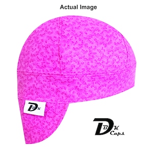 May include: A bright pink durag with a floral pattern. The durag has a flap in the back and a small white tag with the letters "DK" in black. The text "DK Caps" is printed in black on the lower right.