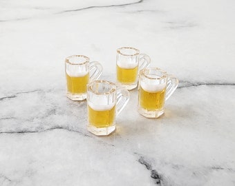 May include: Four miniature glass beer mugs filled with a light yellow liquid. The mugs have a handle and are made of clear glass.