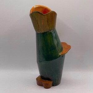 May include: A green and orange ceramic vase with an abstract, asymmetrical design. The vase has a wide opening and a narrow base.