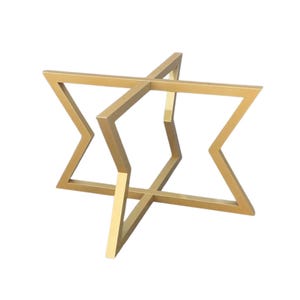 May include: A gold-colored metal decorative table base. The base has a geometric starburst design with intersecting angular supports. The base is made of a sturdy metal and has a smooth finish. The design is modern and minimalist.