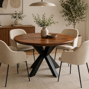 Könnte beinhalten: Ein runder Esstisch aus dunklem Holz, getragen von einem schwarzen, X-förmigen Gestell. Vier beige gepolsterte Stühle mit schwarzen Metallbeinen umgeben den Tisch. Eine Vase mit Grün steht auf dem Tisch und schafft eine moderne Esszimmerumgebung.