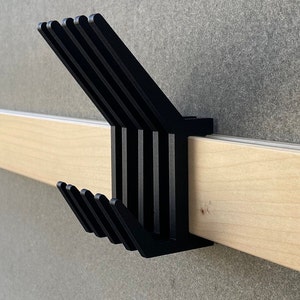 May include: A black wooden wall-mounted coat rack with multiple hooks. The rack is mounted on a light wood shelf.